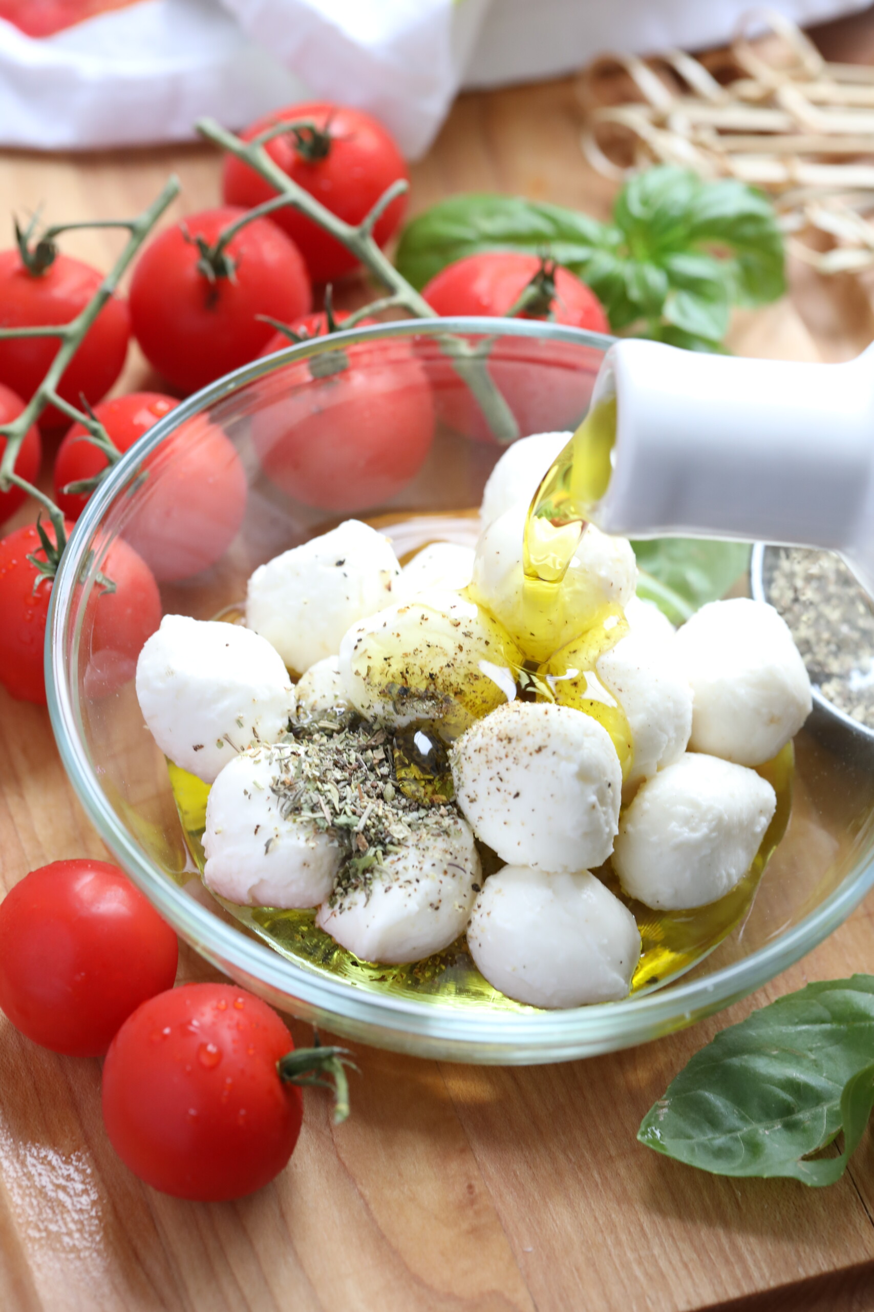 pouring oil over cheese and seasonings to make Caprese Skewers