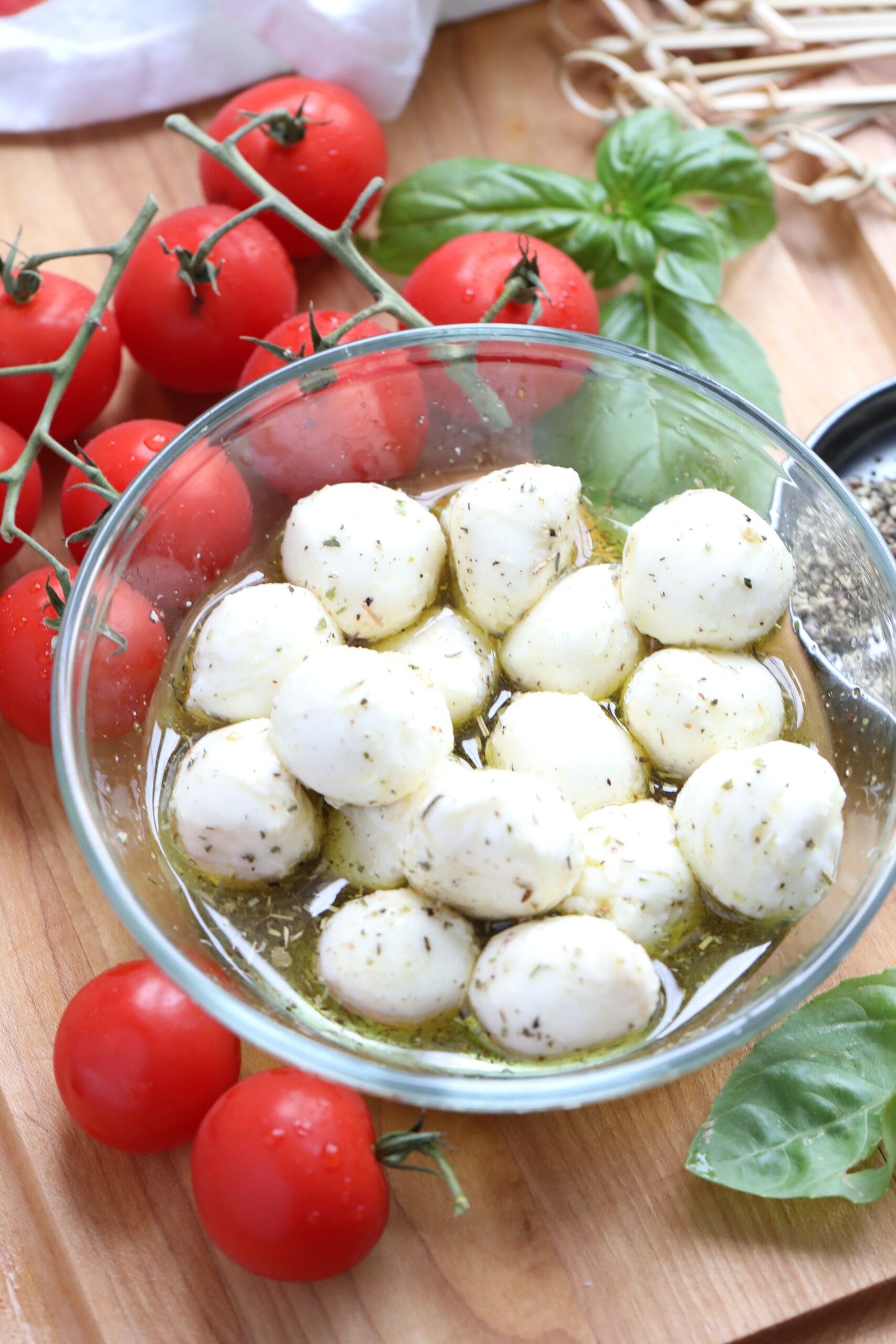 marinated cheese with tomatoes beside it to make Caprese Skewers