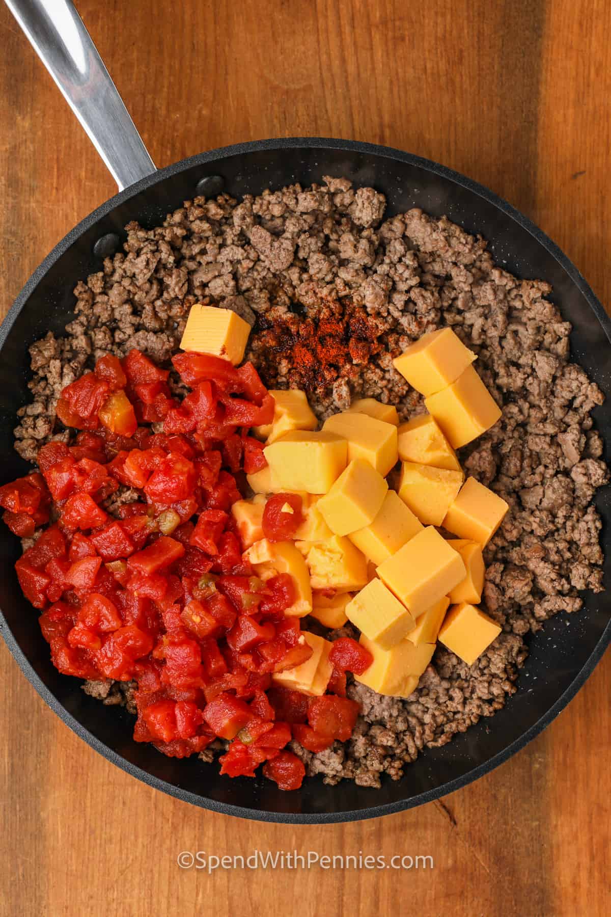 adding ingredients to cooked beef to make Rotel Dip