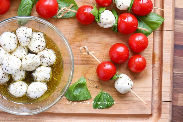 Bowl of mozzarella cheese balls and Caprese Skewers on a cutting board